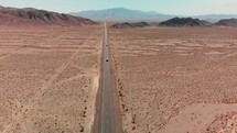 Drone follows a long straight highway through the desert