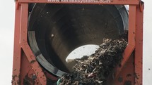 Industrial compost production site. Large rotary compost screening machine filtering compost. Slow motion