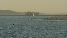 Kayaker, boat, sailboat and shipment container vessel on the water near Pacific Northwest beach