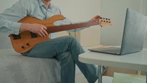 Man practicing guitar skills at home.