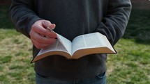  close up of man reading a Bible outdoors 
