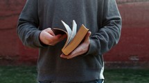 man flipping through the pages of a Bible