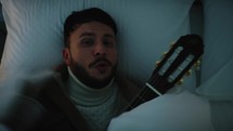 Man sing and Play the guitar in a bed 