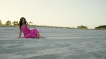Solitude of a girl in a pink dress on the sandy beach