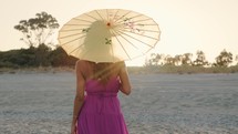 Girl In Pink Dress On Beach with yellow umbrella