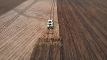 Drone footage. Aerial drone view of tractor plowing on the field. Farmer in tractor preparing land for sowing, cultivation and plows field for planting. Agriculture concept.