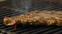 Slow motion of a large beef sirloin steak grilled on a charcoal grill.