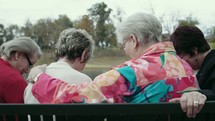 elderly women praying on a park bench 