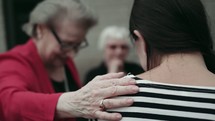 group of elderly women praying over a young woman 