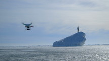 Man Standing On Iceberg with drone filming 