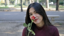 young woman smelling a red rose 