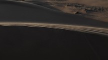 Middle eastern desert, nature landscape. Sand blowing in wind over desert sand dunes in evening desert sunset, sunlight in cinematic slow motion.
