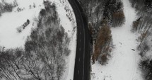 Aerial drone shot of road in Romanian highlands on an overcast winter day.