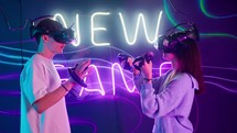 A man and a woman facing each other while playing a virtual reality game.