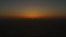 The last light of sun before it sets behind ocean horizon