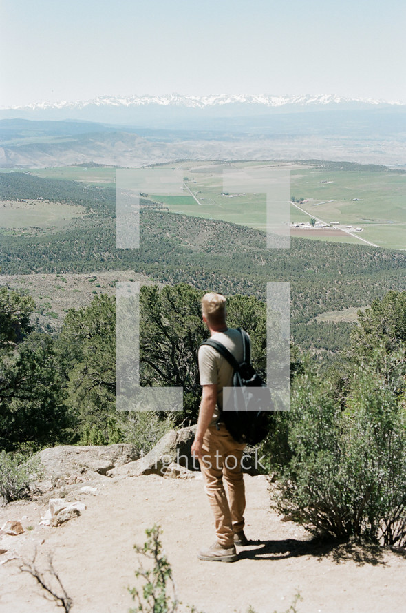 man standing on a mountaintop looking out over a valley 