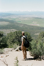 man standing on a mountaintop looking out over a valley 