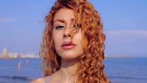 a woman with red hair standing on a shore 