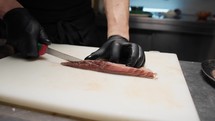 Chef slices salmon for sushi in a Japanese restaurant