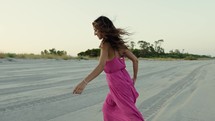 Bare Feet of a girl walking on sandy beach at summer in pink dress