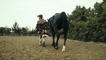 Cowboy walking on the ranch with his black horse