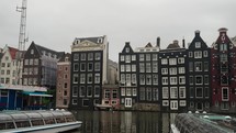 Traditional Houses Along Canal In Amsterdam, Netherlands On Cloudy Day. panning shot