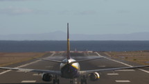 Back view of aircraft departing. Jetliner taking off and ascending over the sea. View with heat distortion