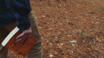  a man carrying a Bible walking into the woods 