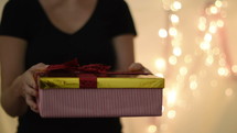 a woman placing a Christmas gift on a table 