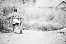 Little African girl running with bike wheel