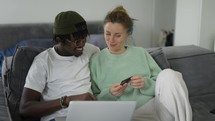 A multiracial couple shopping online, orders a food, makes purchases remotely.