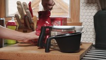 a woman putting coffee grounds in a coffee maker 