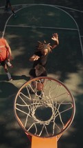 Young men playing basketball on an outdoor court on a sunny day