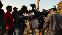 film production crew standing around video cameras outdoors 