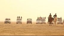 men in SUV's and on horses in the desert 