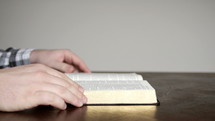 man sitting, opening a Bible, and reading 