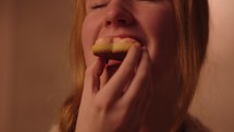 A smiling young woman enjoying a heart shaped Valentine's Day cookie 