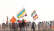 walking in a desert carrying colorful flags and umbrellas for shade 