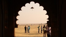 view of men standing in a desert through temple window 