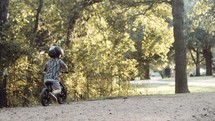  toddler boy riding a bike in a forest 