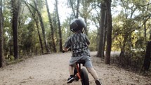 toddler boy riding a bike in a forest 