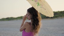 Fashion Pink dressed girl with umbrella on the beach near ocean