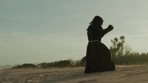 Silhouette Of An Athlete Monk Does Boxing On The Sand Dune