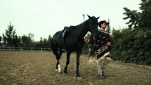 Cowboy walk in the ranch with his black horse
