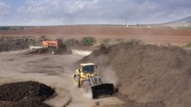 Aerial shot of an Industrial compost production site. Tractors loading compost into machines and trucks