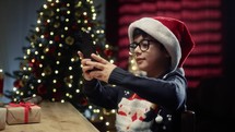 Little Kid typing on smartphone Under Christmas tree 