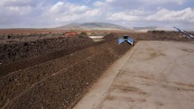 Aerial view of an industrial compost production site. Large compost turning machine mixing compost piles