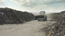 Industrial compost production site. Tractors loading compost into screening machines and trucks. Slow motion