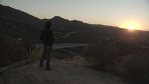 a man looking out into the setting sun 