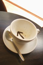 Tea leaves in a tea cup in the shape of an arrow